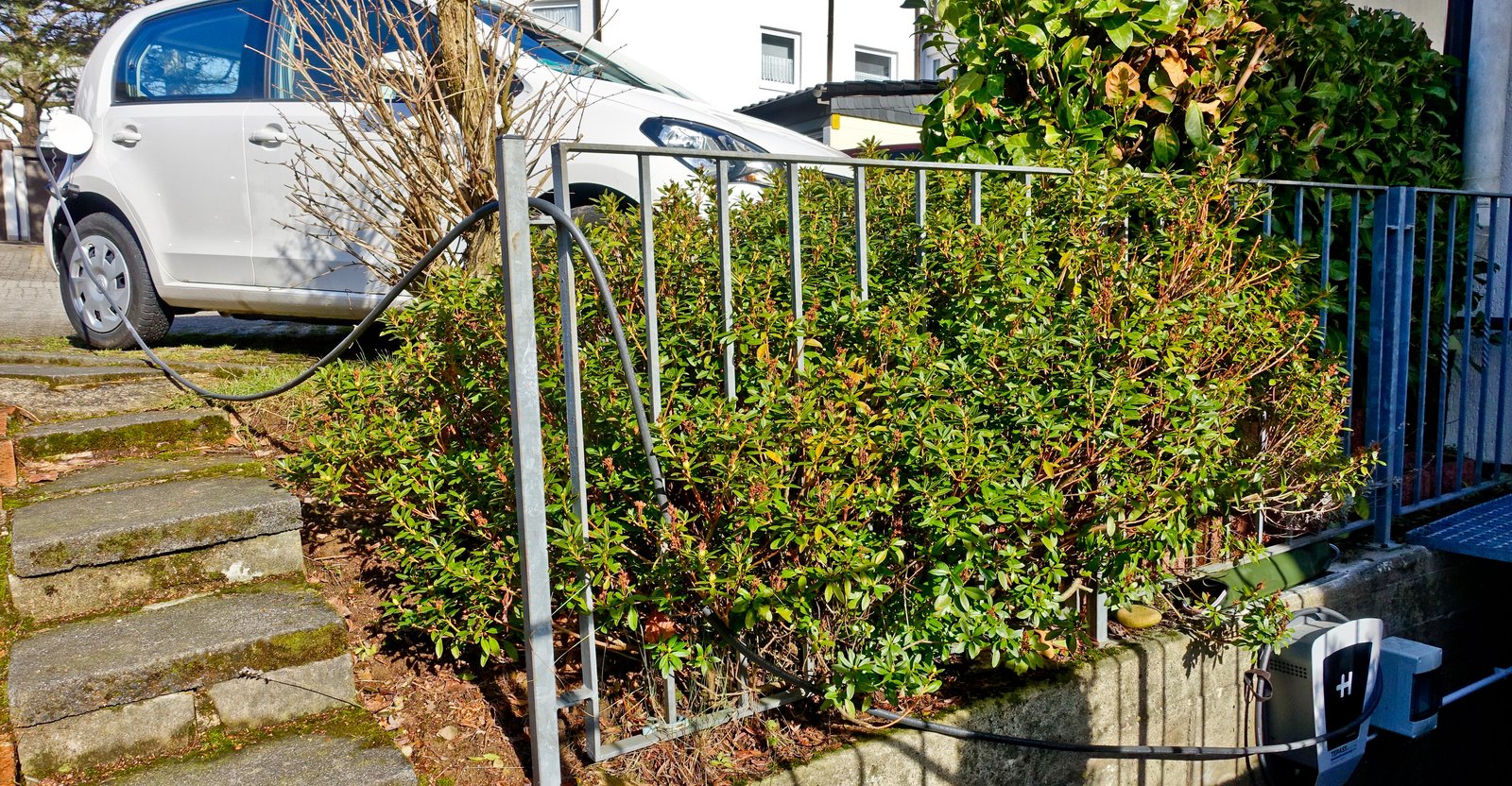 Wallbox genérico instalado en el exterior de una vivienda, con el cable de carga conectado a un auto eléctrico (imagen genérica, no corresponde al modelo Besen específico)