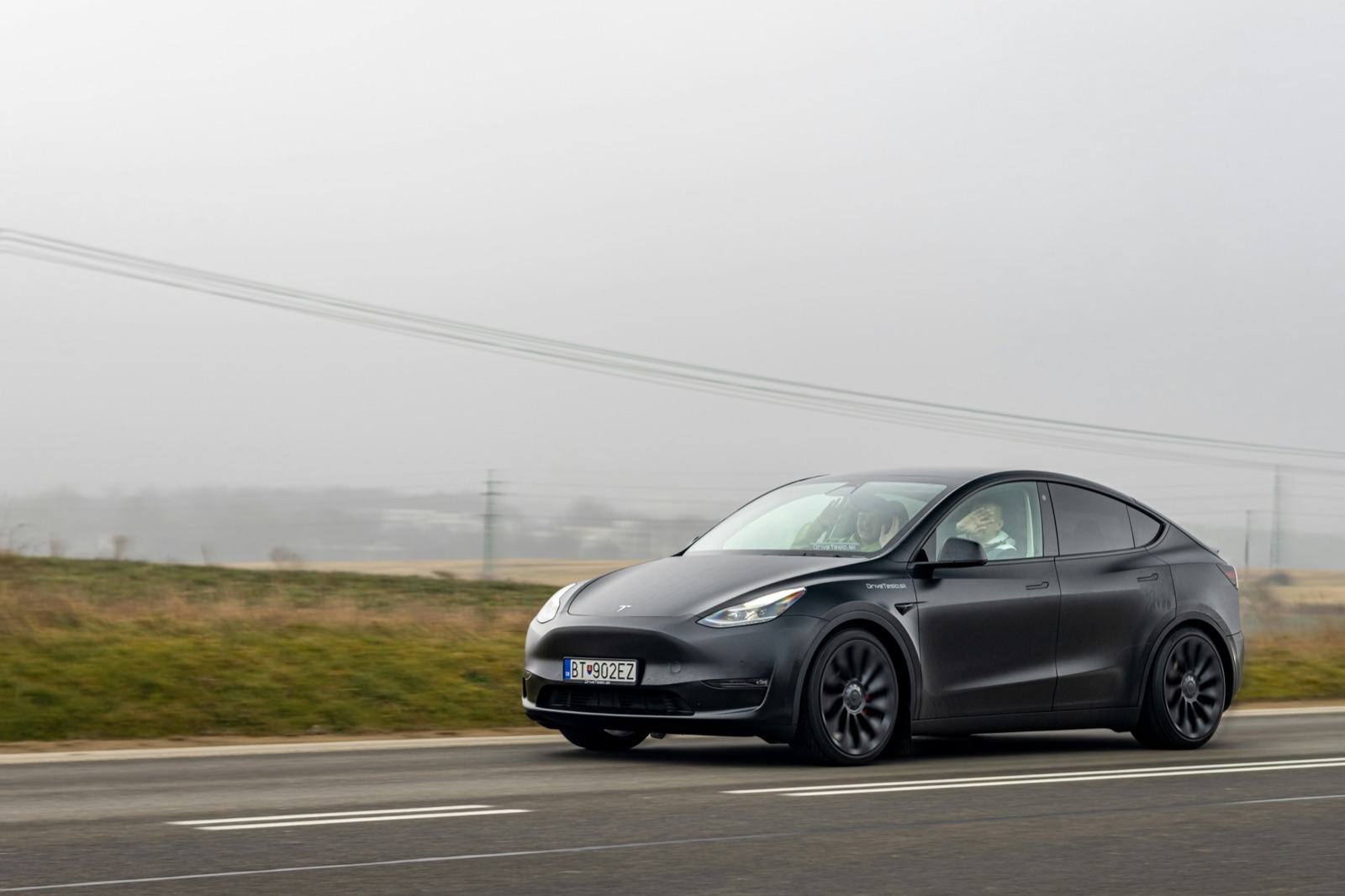 Tesla Model Y negro circulando por una ruta con niebla