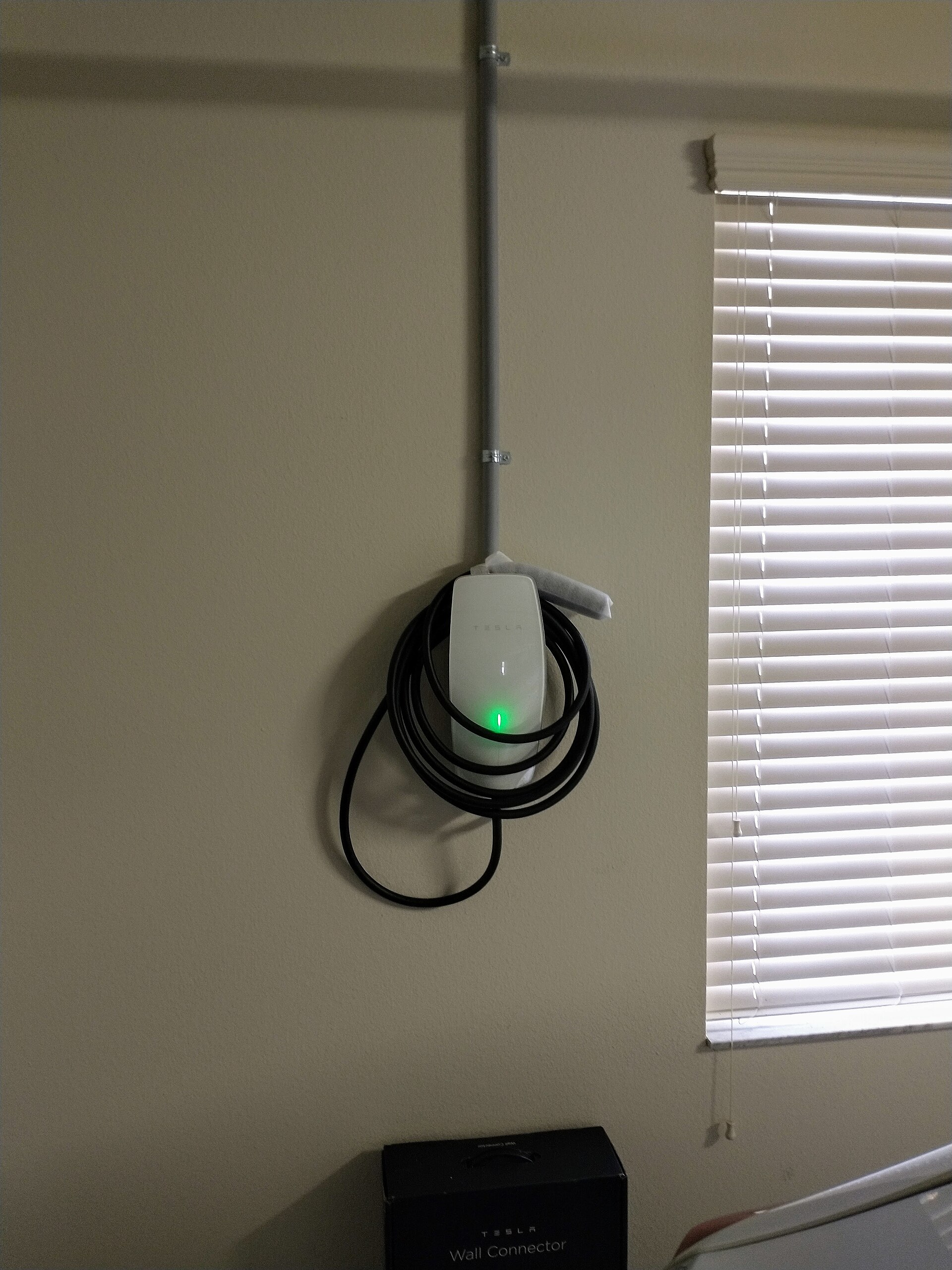 Tesla Wall Connector instalado en la pared de un garaje, con el cable enrollado