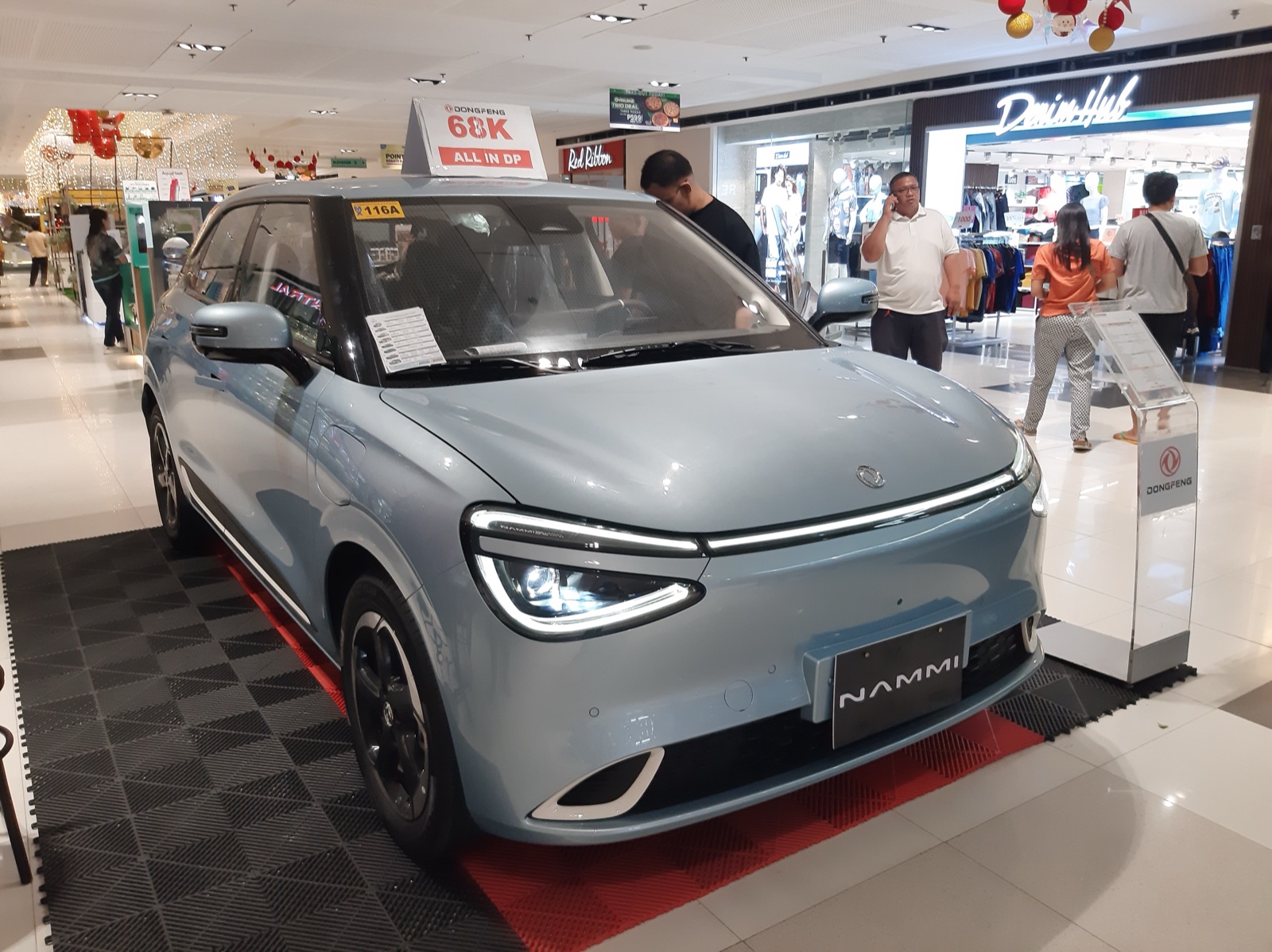 Dongfeng Nammi celeste en exhibición dentro de un shopping, vista frontal tres cuartos