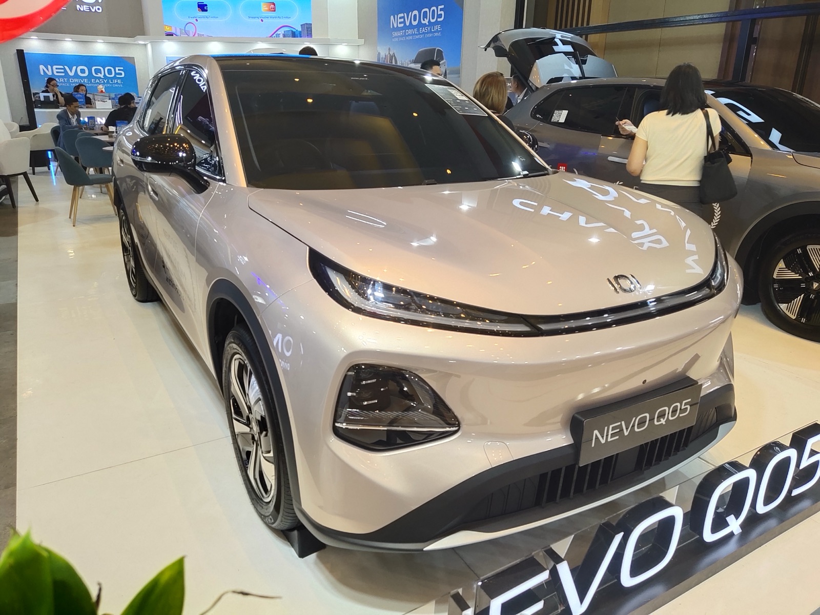 Changan Nevo Q05 EV beige en el stand de Nevo del salón GIIAS 2026, vista frontal tres cuartos